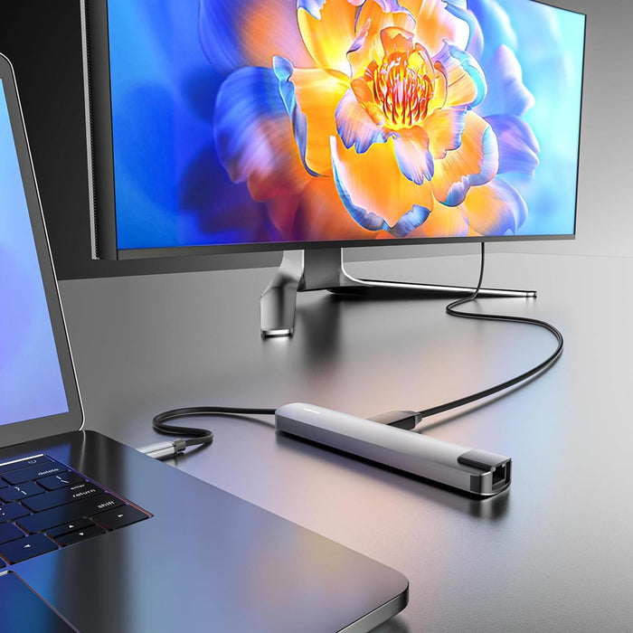 Laptop with a USB-C adapter connected to a monitor displaying a colorful flower image.